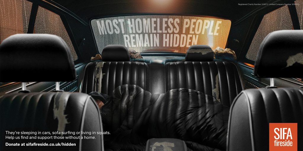 Poster for homeless charity SIFA that shows a person asleep on the back seat of a car. Their sleeping bag blends in to the pattern of the seat so you don't see them at first. Headline reads Most Homeless People Remain Hidden.